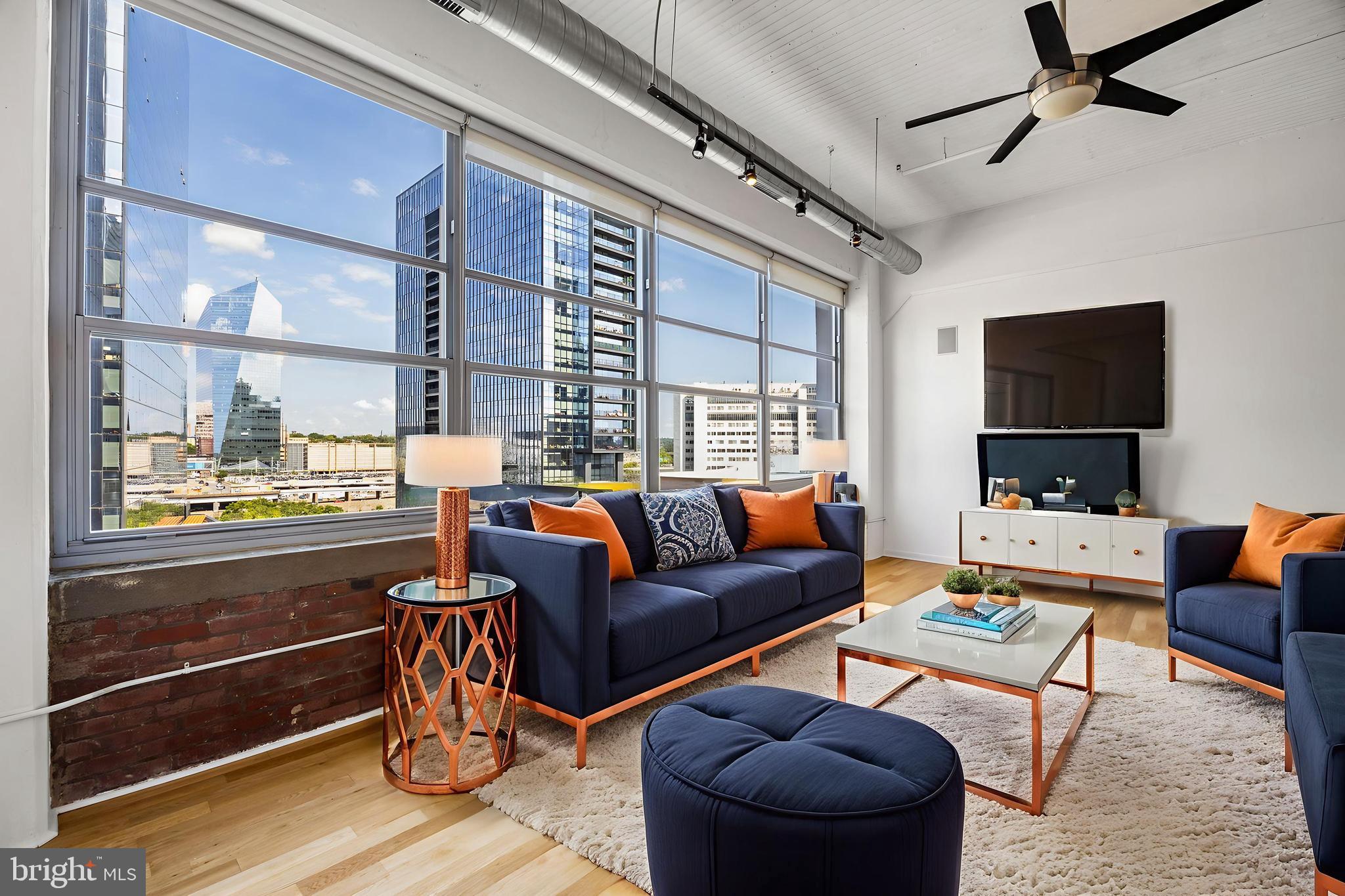 2200-28 Arch Street, Unit 716 Philadelphia, PA 19103 - Photo 2 of 35 a living room with furniture a flat screen tv and a floor to ceiling window