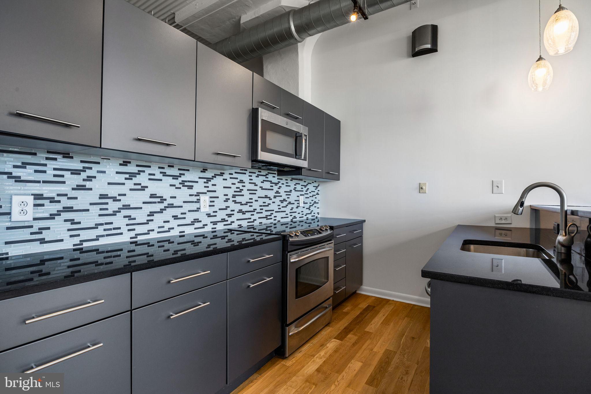 2200-28 Arch Street, Unit 716 Philadelphia, PA 19103 - Photo 7 of 35 a kitchen with granite countertop a sink and a stove top oven