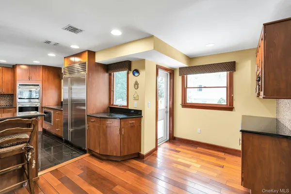 a kitchen with stainless steel appliances granite countertop a refrigerator a sink a stove a microwave and wooden floor