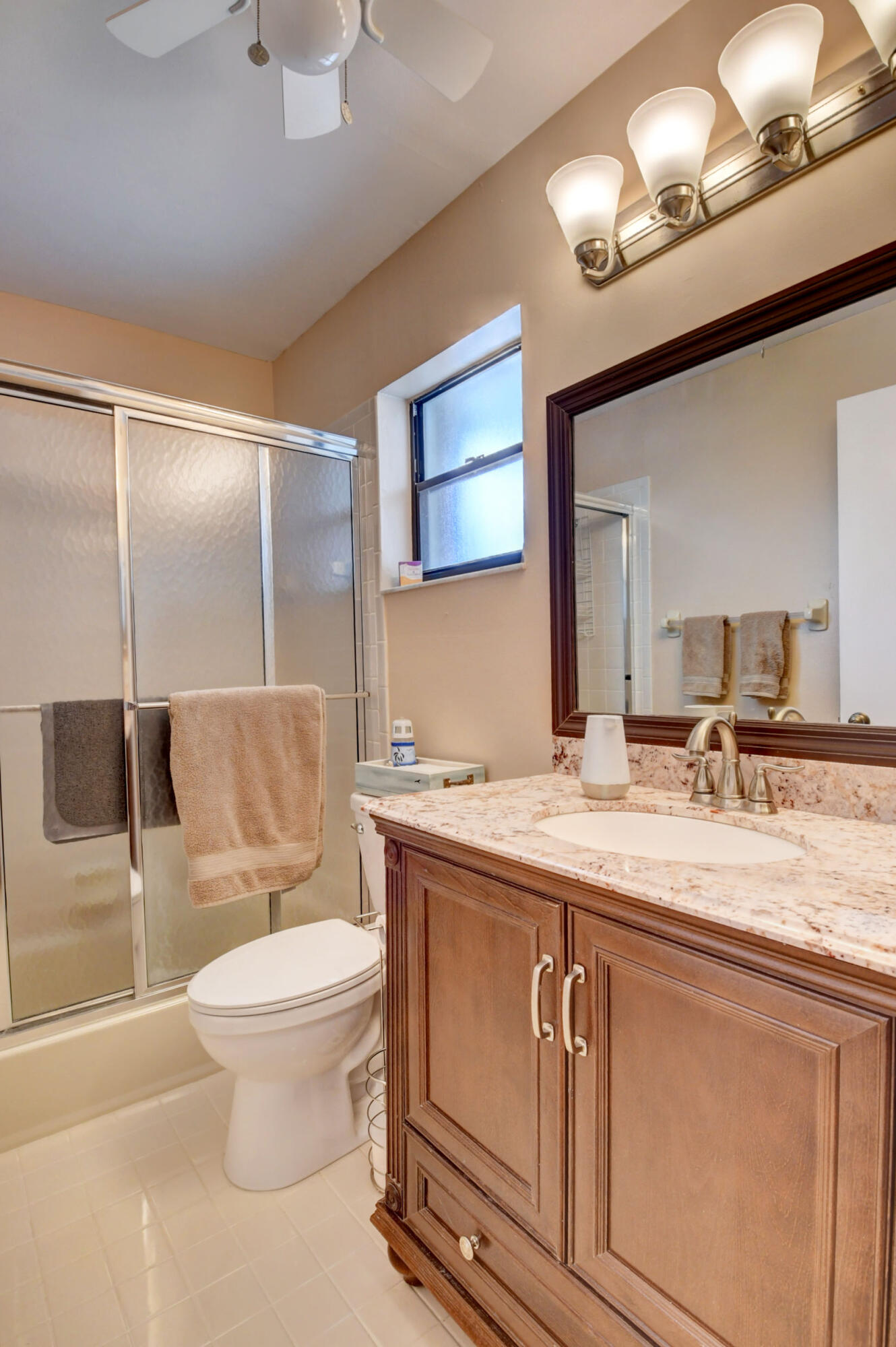 9142 Southwest 22nd Street, Unit D Boca Raton, FL 33428 - Photo 19 of 36 a bathroom with a granite countertop sink a toilet and a mirror