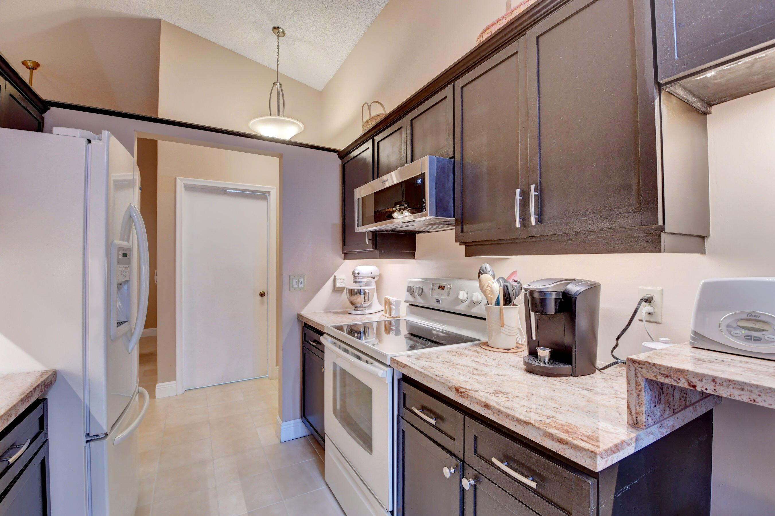 9142 Southwest 22nd Street, Unit D Boca Raton, FL 33428 - Photo 9 of 36 a kitchen with granite countertop a sink a stove and a refrigerator