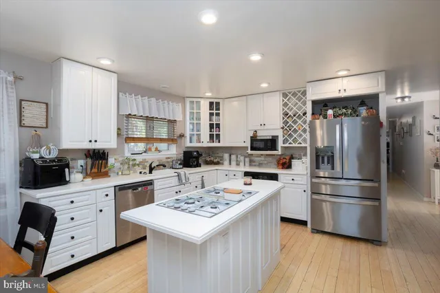 a kitchen that has a lot of white cabinets and stainless steel appliances