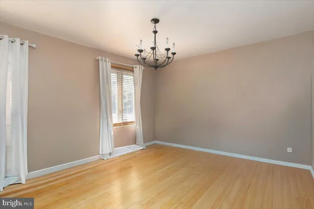 a view of empty room with wooden floor and chandelier