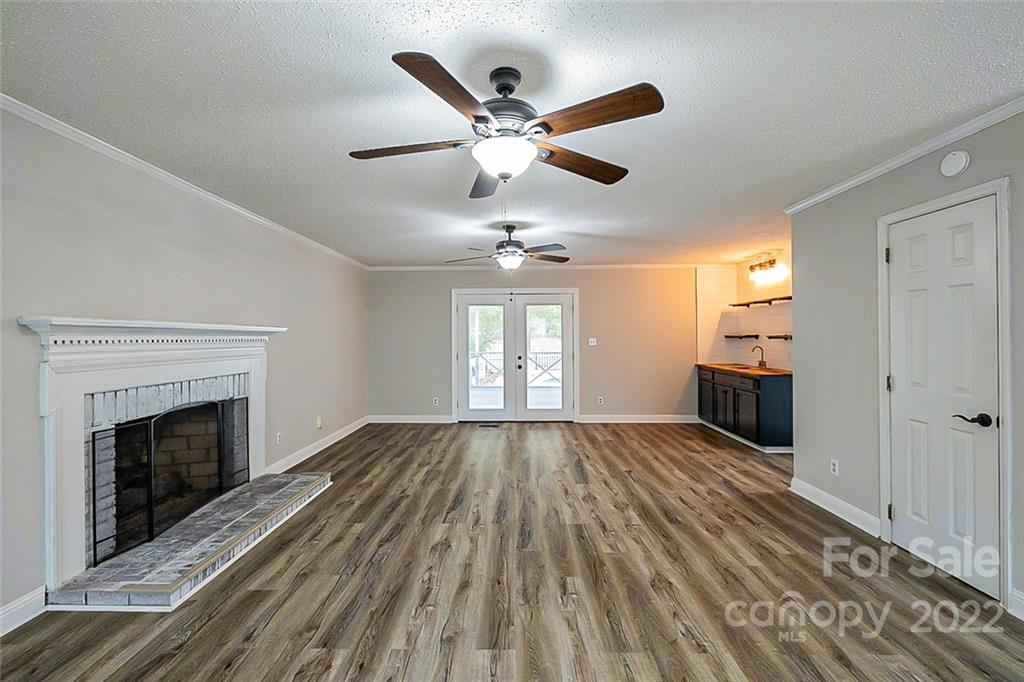 2927 Trotters Road Gastonia, NC 28054 - Photo 3 of 16 an empty room with wooden floor fireplace and windows