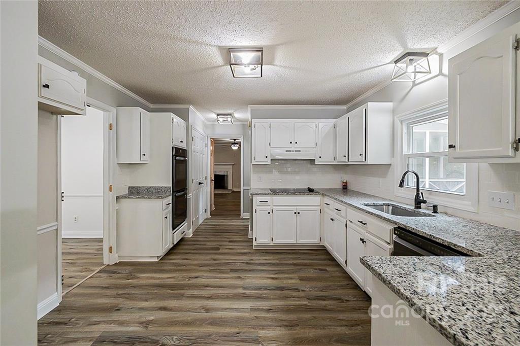 2927 Trotters Road Gastonia, NC 28054 - Photo 5 of 16 a large kitchen with kitchen island granite countertop a stove a sink a refrigerator and white cabinets with wooden floor