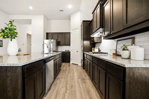 a kitchen with stainless steel appliances granite countertop a sink a stove top oven a counter space and cabinets