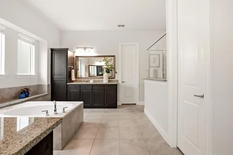 a bathroom with a granite countertop bathtub a sink and a mirror