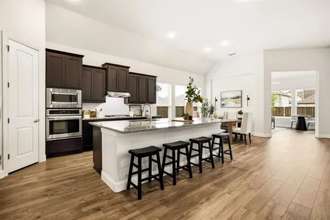 a kitchen with stainless steel appliances a dining table chairs and wooden floor