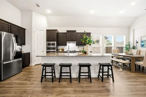 a kitchen with stainless steel appliances granite countertop a table chairs sink refrigerator and microwave