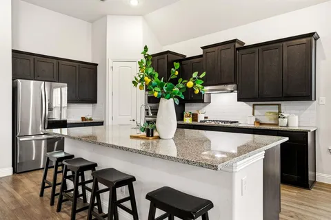 a kitchen with stainless steel appliances granite countertop a table chairs and a refrigerator