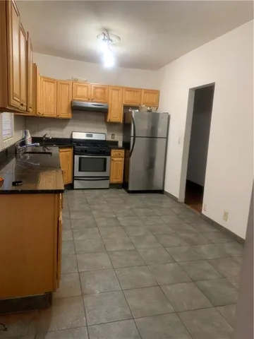 a kitchen with granite countertop a refrigerator and a stove top oven