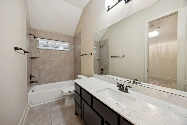 a bathroom with a granite countertop sink a toilet a mirror and bathtub