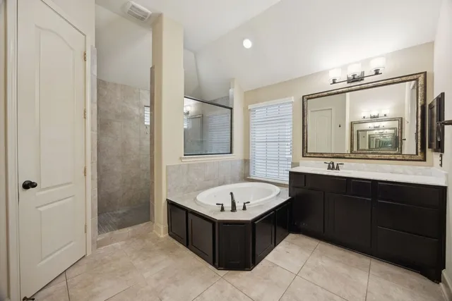 a spacious bathroom with a tub sink shower and mirror