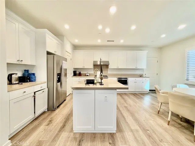 a kitchen with stainless steel appliances granite countertop a refrigerator sink and white cabinets