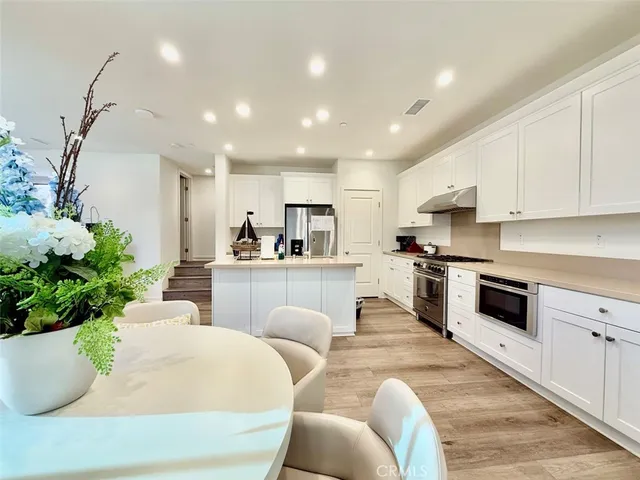 a living room with stainless steel appliances kitchen island granite countertop furniture a sink a rug and a potted plant