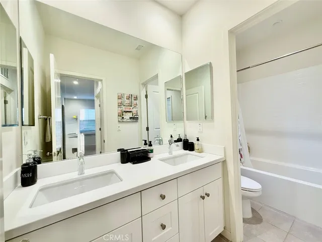 a bathroom with a double vanity sink toilet mirror and bathtub