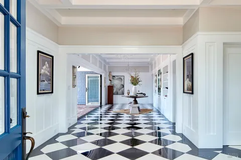 a living room with a black white checkered floor with couches chair and a coffee table