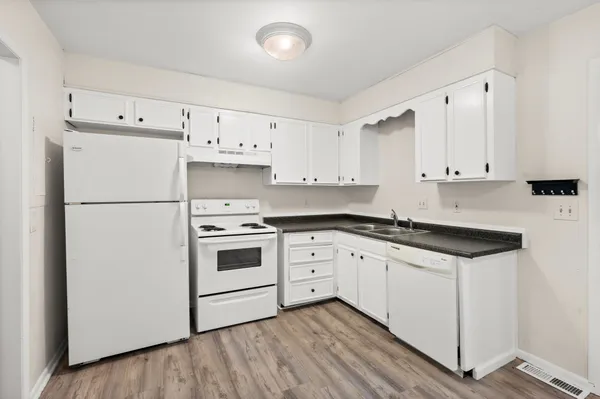 a kitchen with granite countertop white cabinets and white appliances