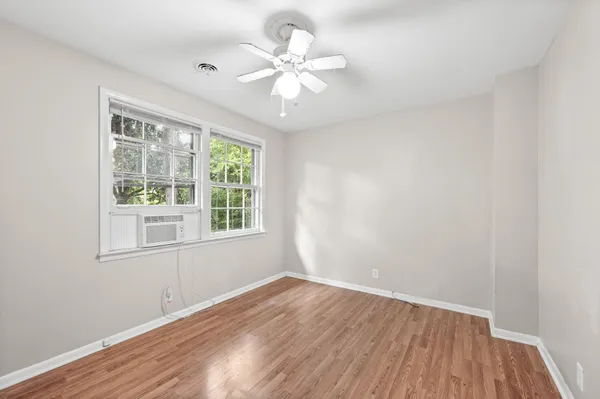 a view of an empty room with wooden floor and a window