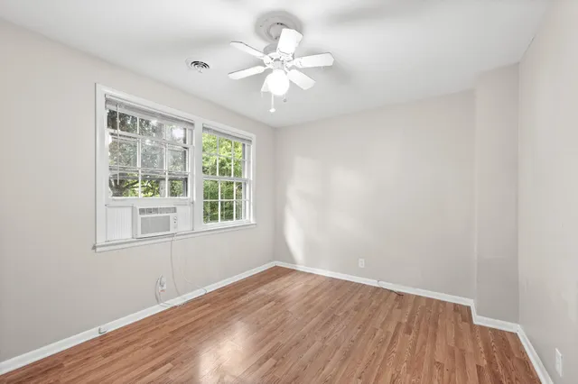 a view of an empty room with wooden floor and a window