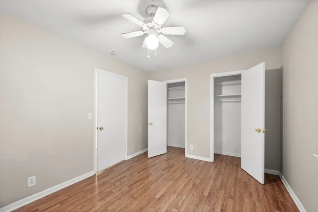 an empty room with wooden floor and ceiling fan