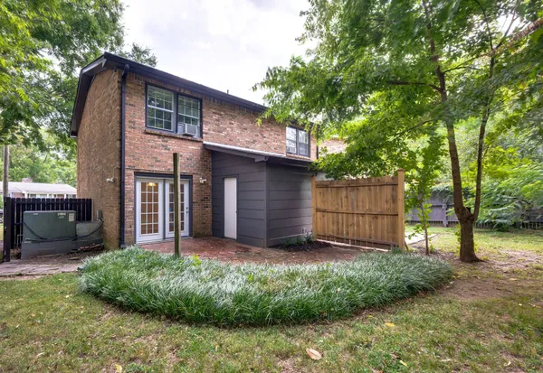 a view of a small house with a small yard plants and large tree