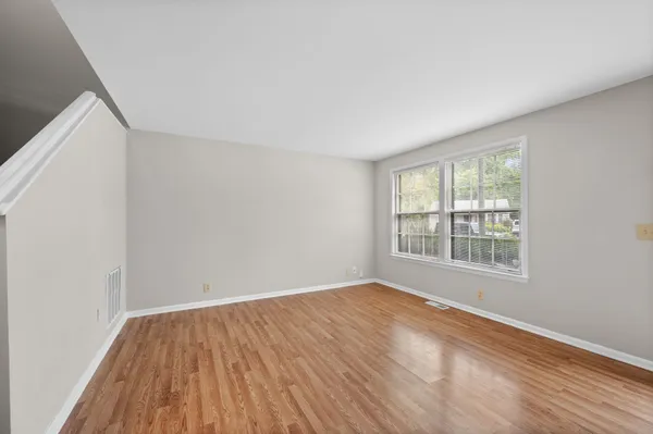 a view of an empty room with wooden floor and a window