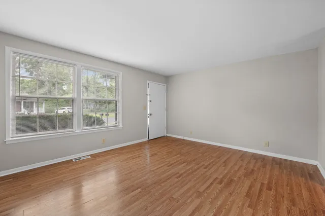 an empty room with wooden floor and windows