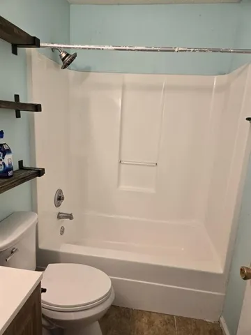 a white toilet sitting next to a bath tub