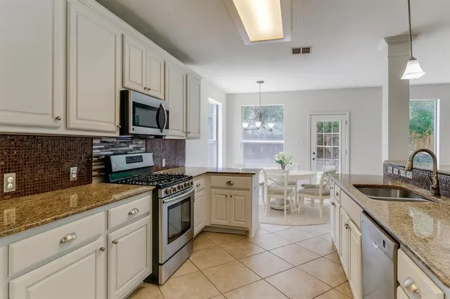 a kitchen with granite countertop sink stainless steel appliances and white cabinets