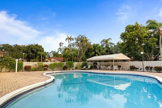 a view of a swimming pool with lawn chairs under an umbrella