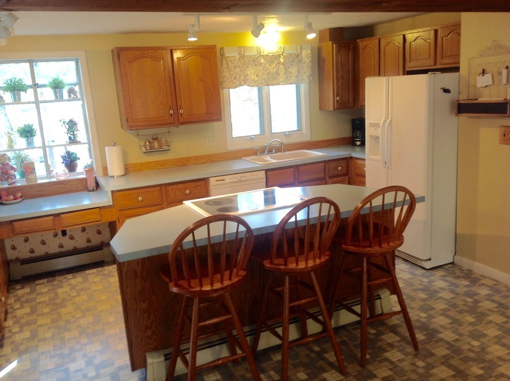99 Keyes Road Westford, MA 01886 - Photo 3 of 20 a kitchen with stainless steel appliances a table chairs and a refrigerator