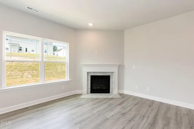 an empty room with wooden floor a ceiling fan and windows