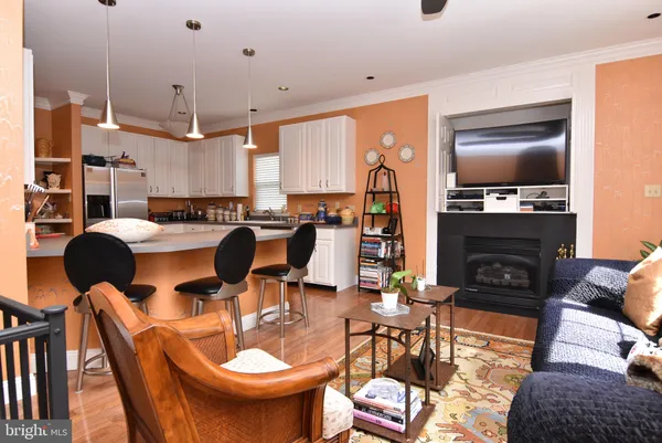 a kitchen with stainless steel appliances kitchen island granite countertop a refrigerator a stove top oven a dining table and chairs with wooden floor