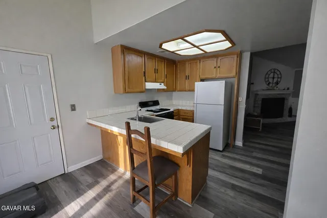 a kitchen with a stove a sink and wooden floor