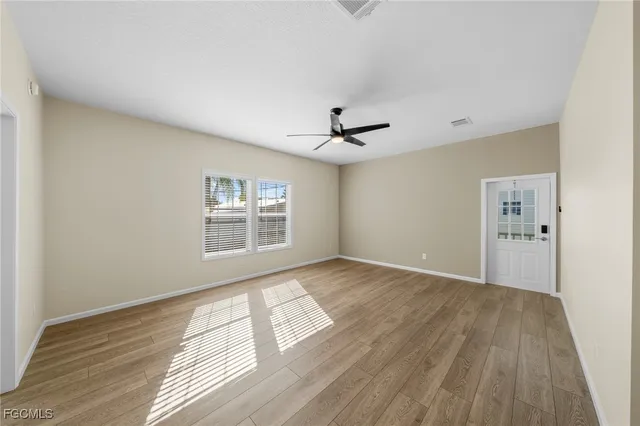 a view of an empty room with wooden floor and a window