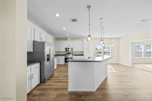 a large kitchen with stainless steel appliances kitchen island a large counter top and wooden floors