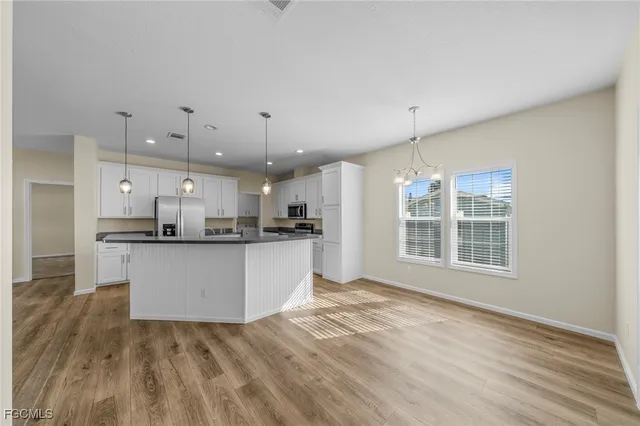 a view of a kitchen with kitchen island a sink wooden floor and a counter top space