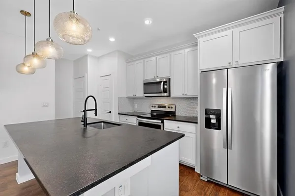 a kitchen with stainless steel appliances granite countertop a sink a refrigerator and a stove top oven