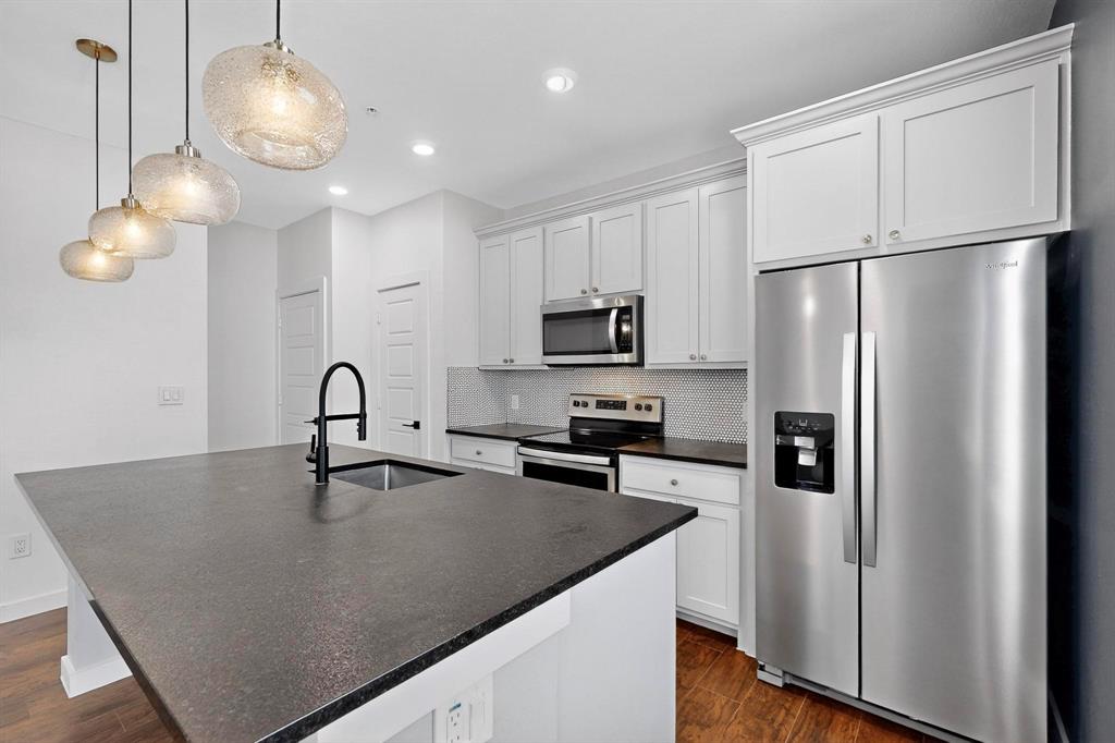 800 South Welch Street, Unit 102 Denton, TX 76201 - Photo 2 of 15 a kitchen with stainless steel appliances granite countertop a sink a refrigerator and a stove top oven