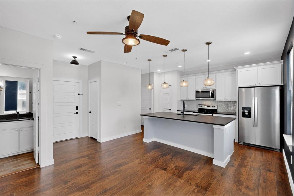 800 South Welch Street, Unit 102 Denton, TX 76201 - Photo 4 of 15 a kitchen with stainless steel appliances a stove a refrigerator a sink a oven and white cabinets with wooden floor