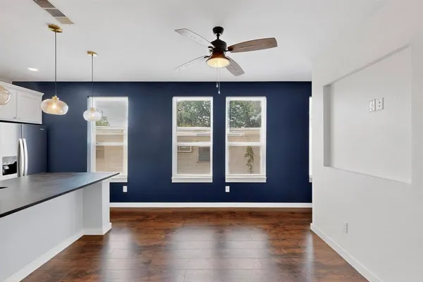 a view of an empty room with window and wooden floor