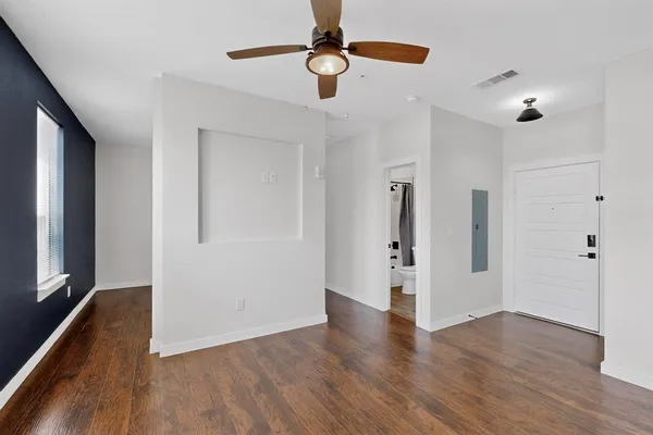 a view of an empty room with wooden floor and a window