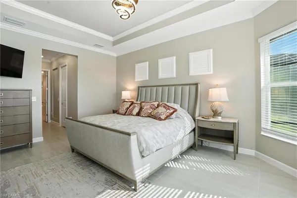 a large bed sitting in a bedroom next to a window and a chandelier