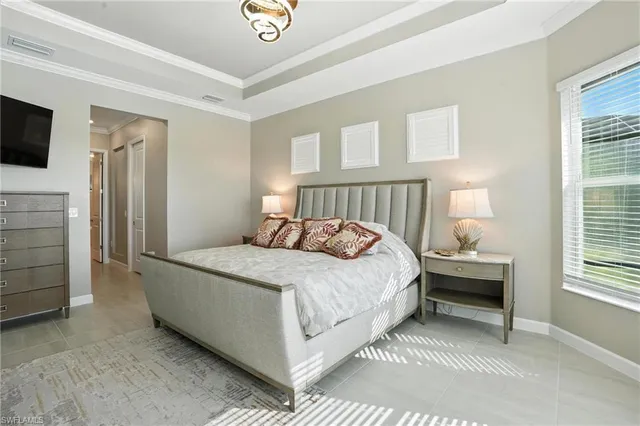 a large bed sitting in a bedroom next to a window and a chandelier