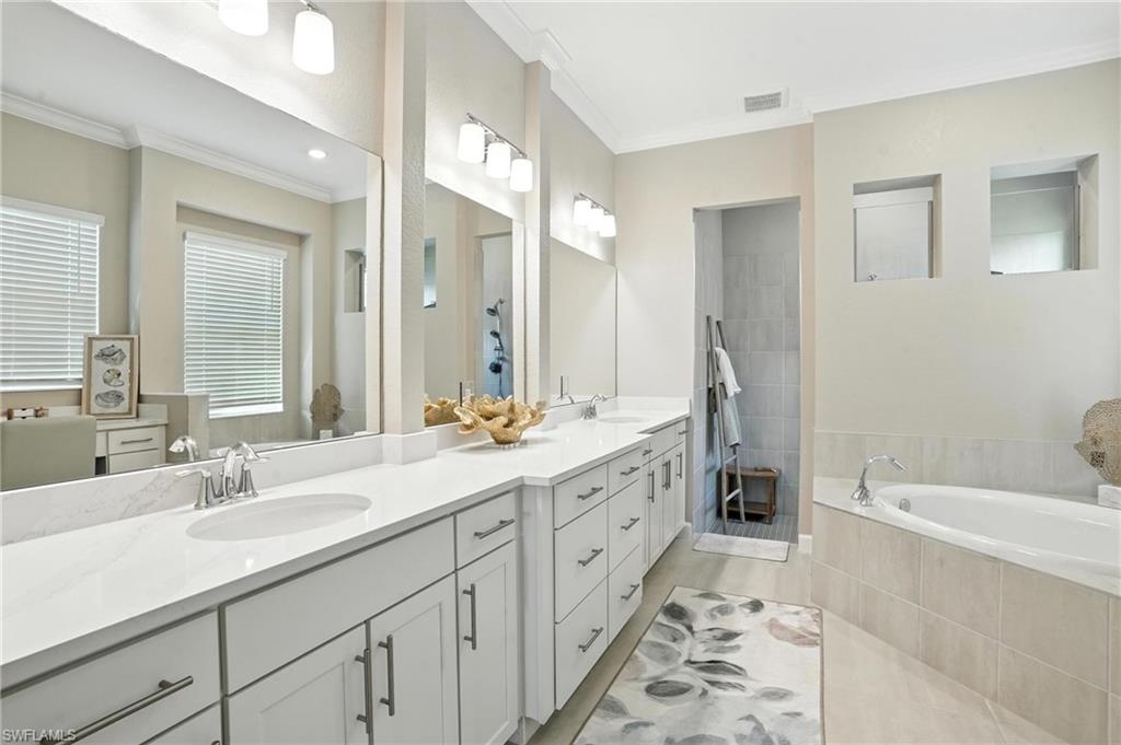 15027 Longs Lane Babcock Ranch, FL 33982 - Photo 27 of 50 a bathroom with double vanity sinks a toilet a mirror and a bathtub