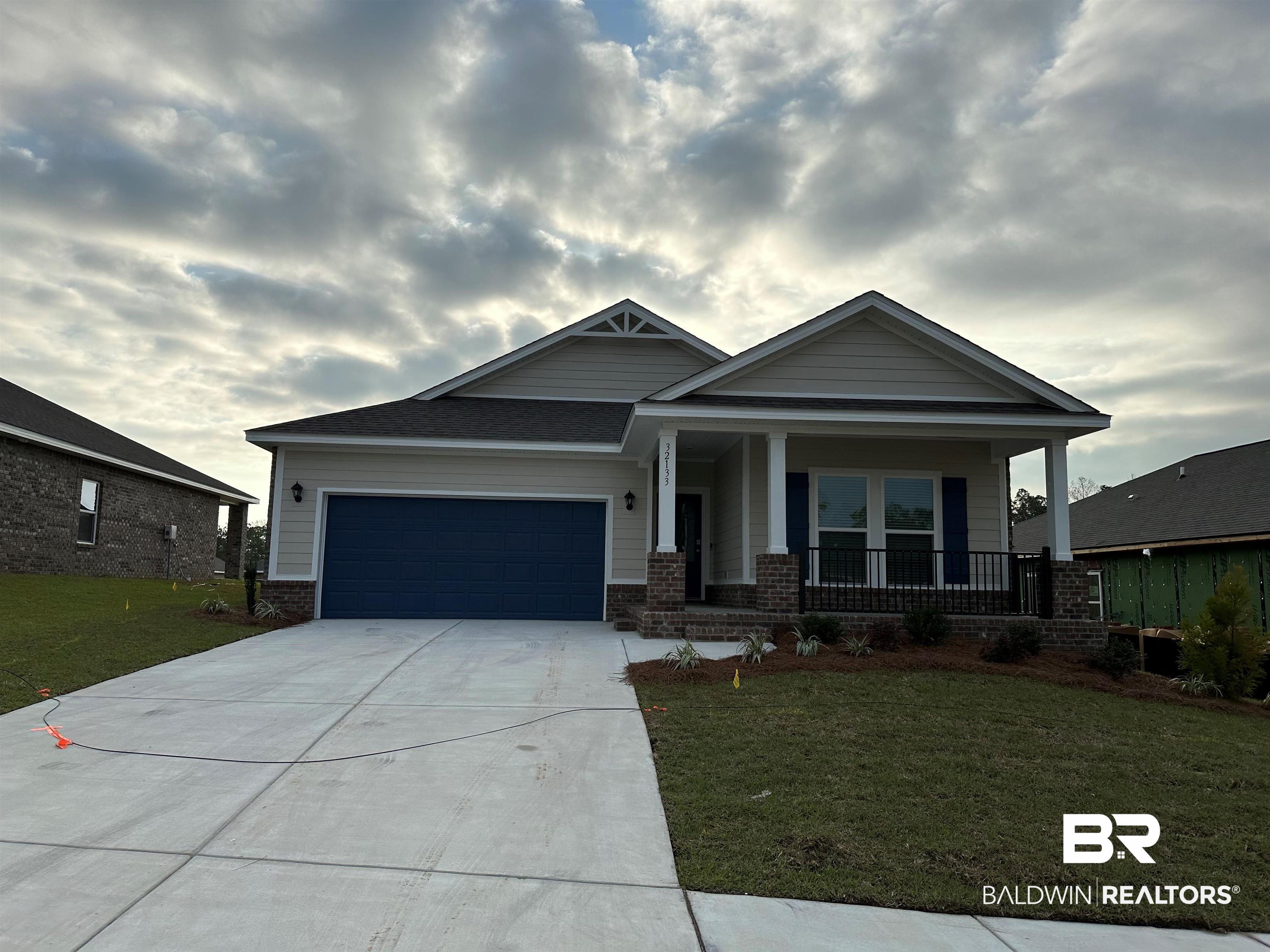 32133 Lyon Road Daphne, AL 36527 - Photo 1 of 35 Craftsman-style house featuring a garage, concrete driveway, brick siding, a front lawn, and covered porch