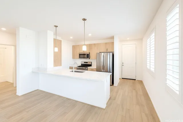 a kitchen with stainless steel appliances a refrigerator a sink dishwasher a stove and white cabinets with wooden floor