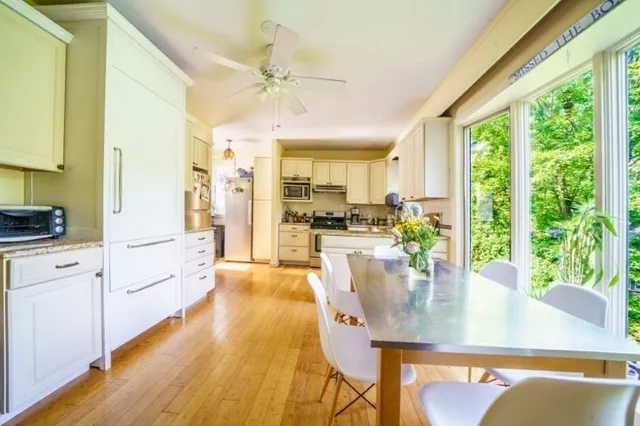 a view of a kitchen with kitchen island a large window cabinets a sink and stainless steel appliances