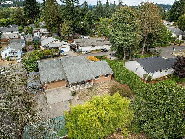 an aerial view of residential house with outdoor space and trees all around